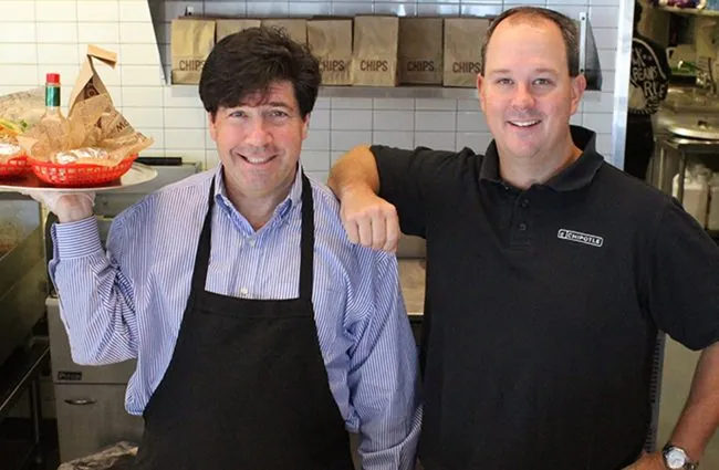 Two men smiling at camera in chipotle