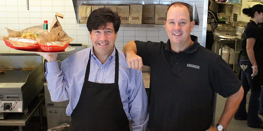 Two men smiling at camera in chipotle