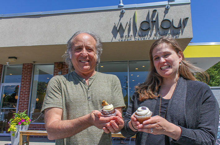 Wildflour owner and Linear employee standing in front of the storefront with cupcakes